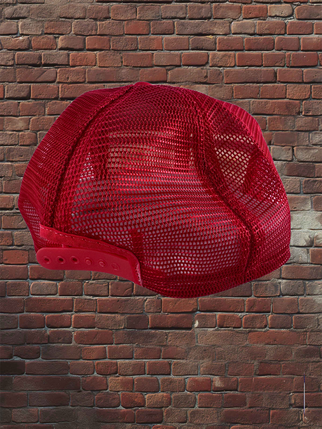 A red trucker-style cap with a red mesh back and solid front panels, shown floating against a red brick wall background.