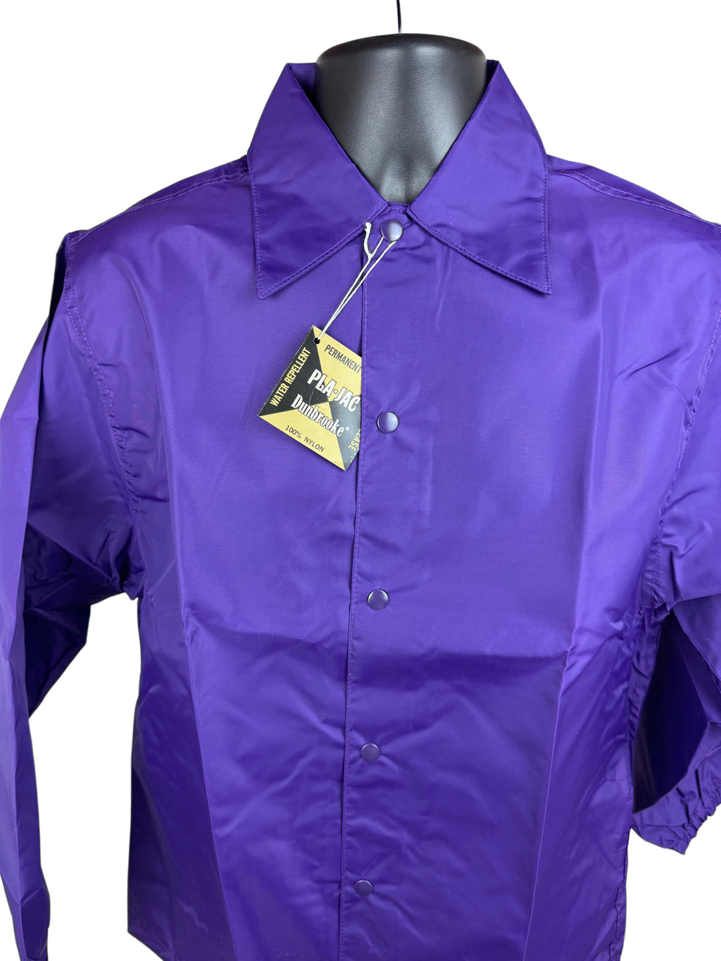 A purple long-sleeve snap-front nylon jacket displayed on a black mannequin torso against a white background, with a yellow and black hangtag attached near the collar.