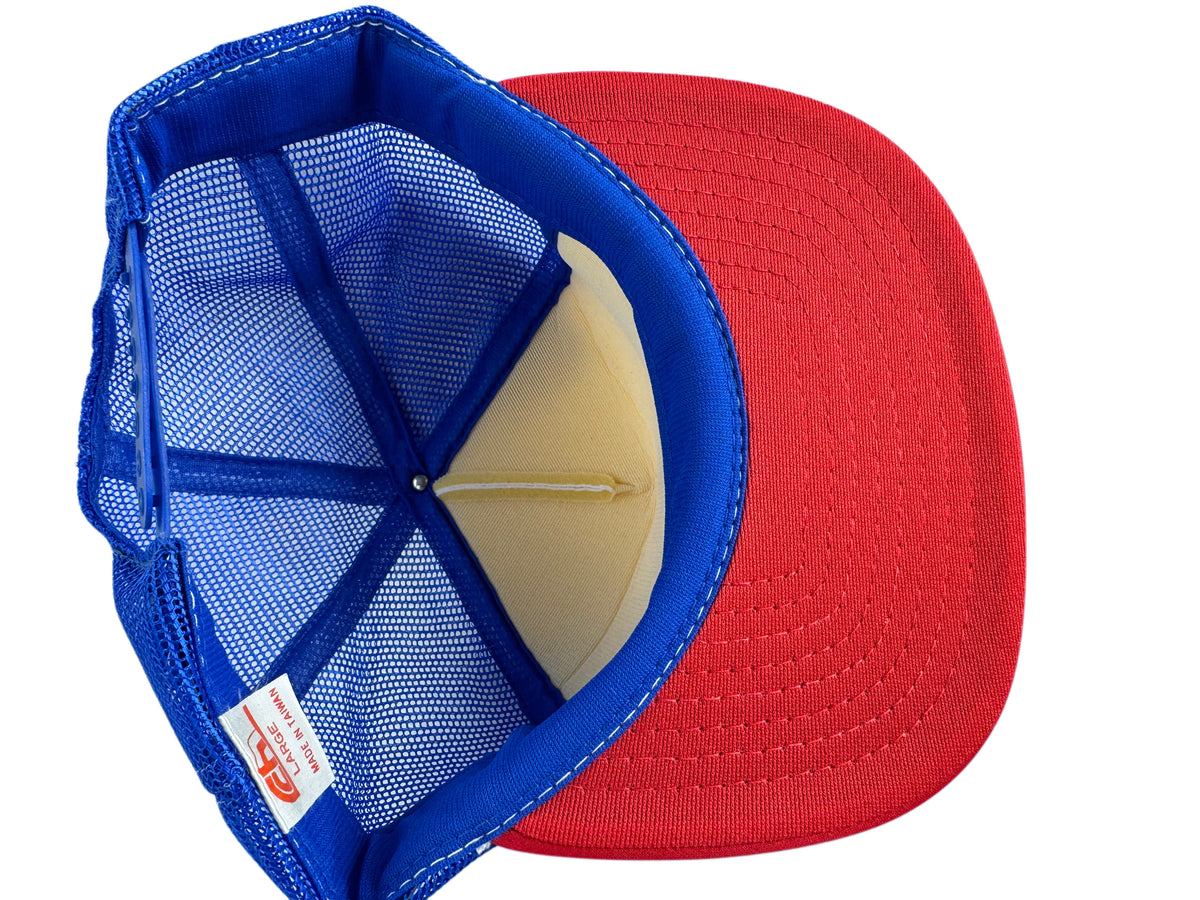 A red and blue trucker-style baseball cap shown from an overhead angle, revealing the blue mesh back, blue fabric lining, and a beige inner crown. A small red and white brand tag is visible on the side.