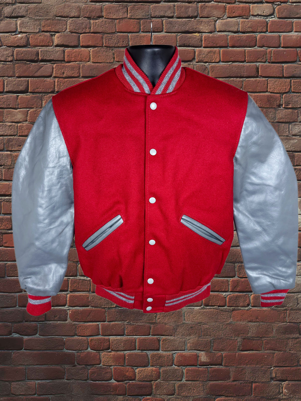 A red and silver varsity jacket displayed on a black mannequin torso against a brown brick wall background.