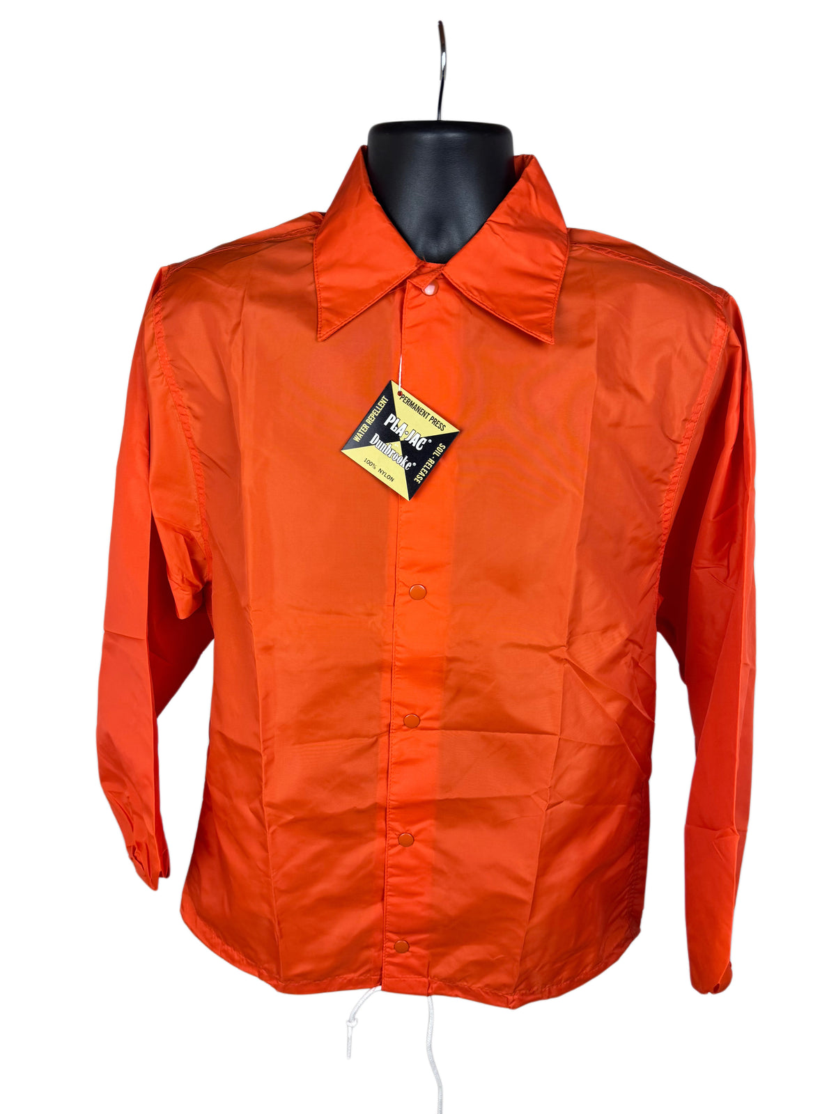 Bright orange long-sleeve snap-front jacket displayed on a black mannequin torso against a plain white background, with a yellow and black diamond-shaped hangtag attached near the collar.