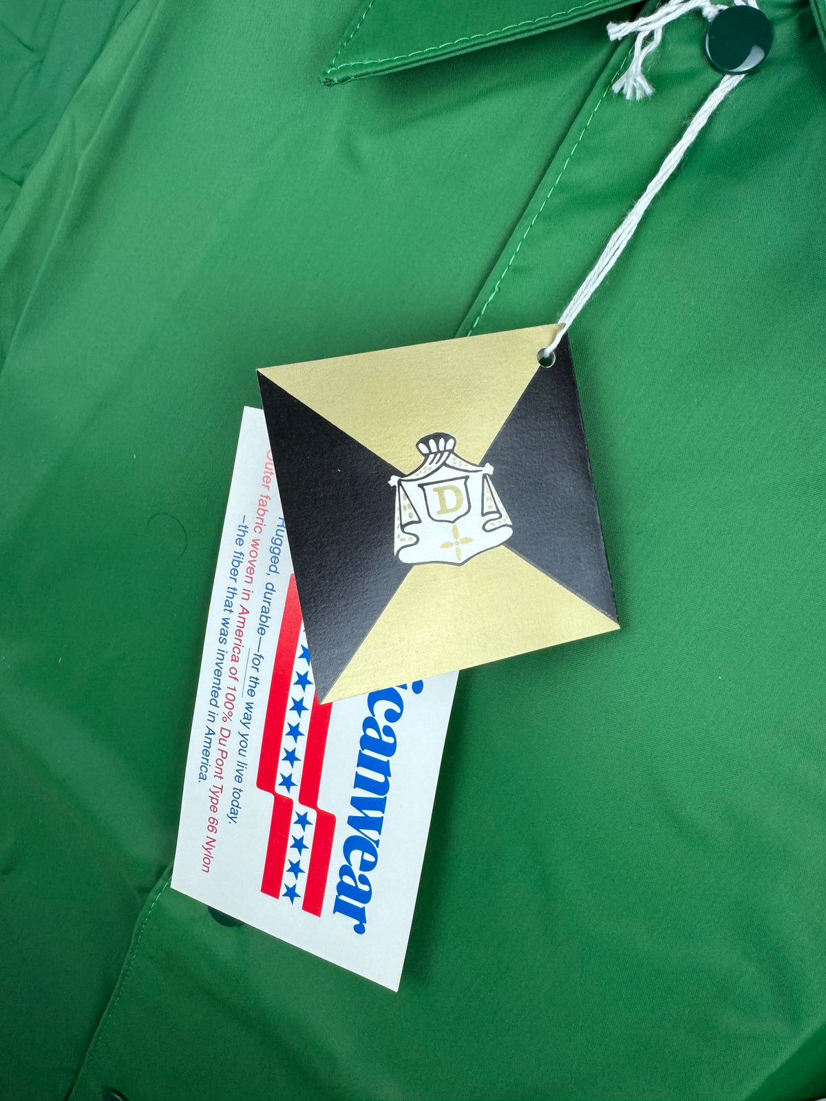A close-up of a green garment with a gold, black, and white hangtag attached. A paper tag reading 'Americanwear' is partially visible underneath.