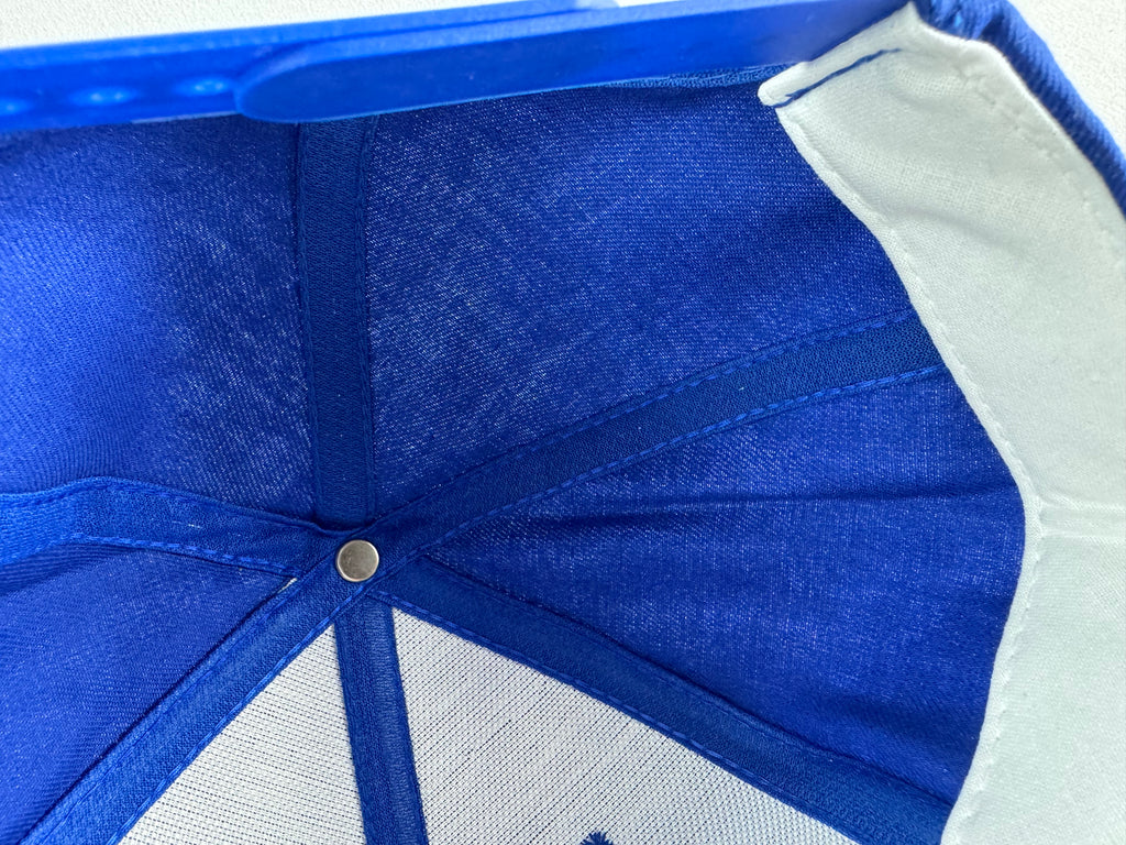 Close-up of the inside crown of a blue and white baseball cap, showing the fabric panels, metal snap closure, and white mesh side panels.