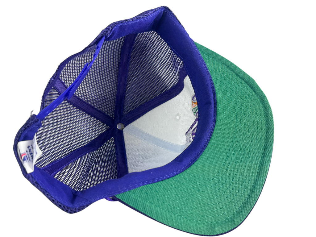 A trucker-style baseball cap shown from an angled top view, featuring a green visor, a blue mesh back, and a blue fabric lining.
