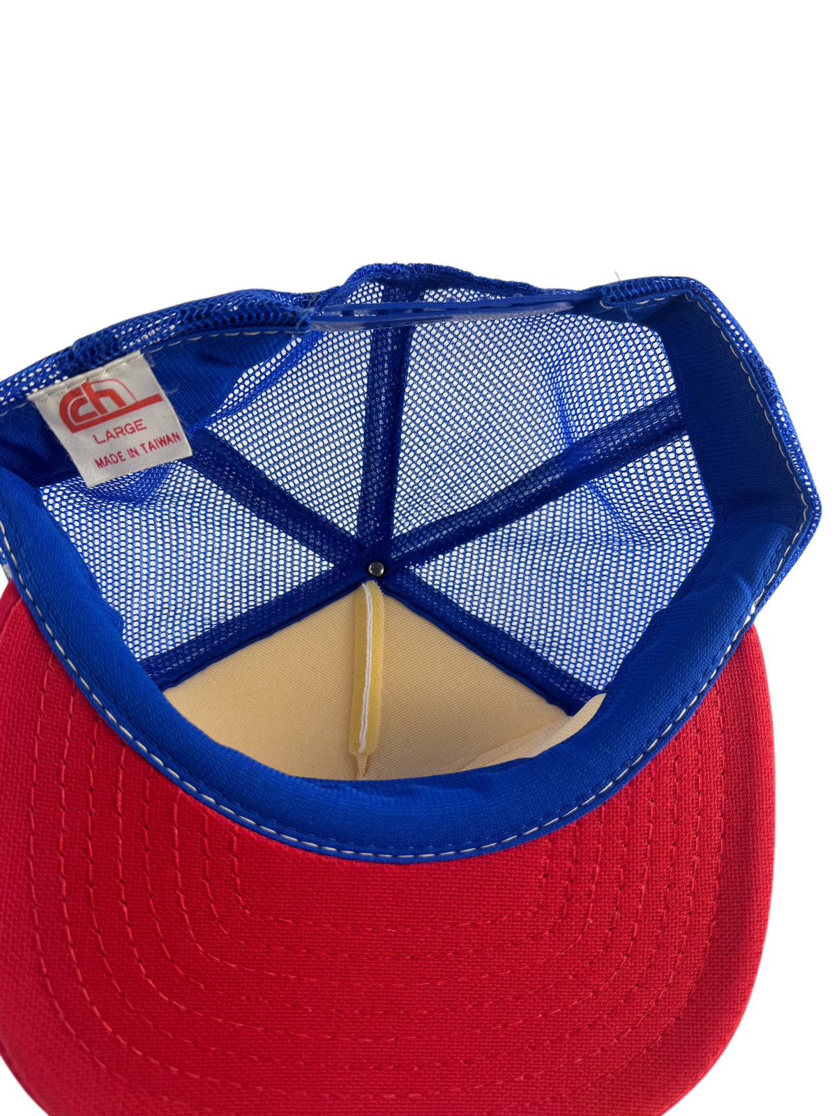 Close-up of the back of a red and blue trucker hat, showing the blue mesh back, blue fabric trim, and a red visor on a white background.