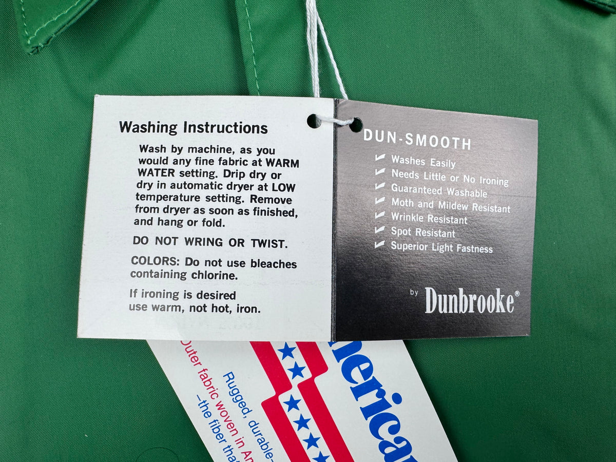 Two hanging product care and material tags on a green fabric surface. The left tag is white and reads 'Washing Instructions.