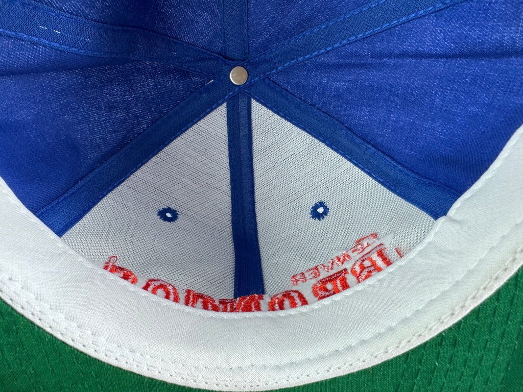 Close-up of the inside crown of a baseball cap showing blue fabric panels, a white fabric lower panel with embroidered red lettering, and a white curved brim edge.