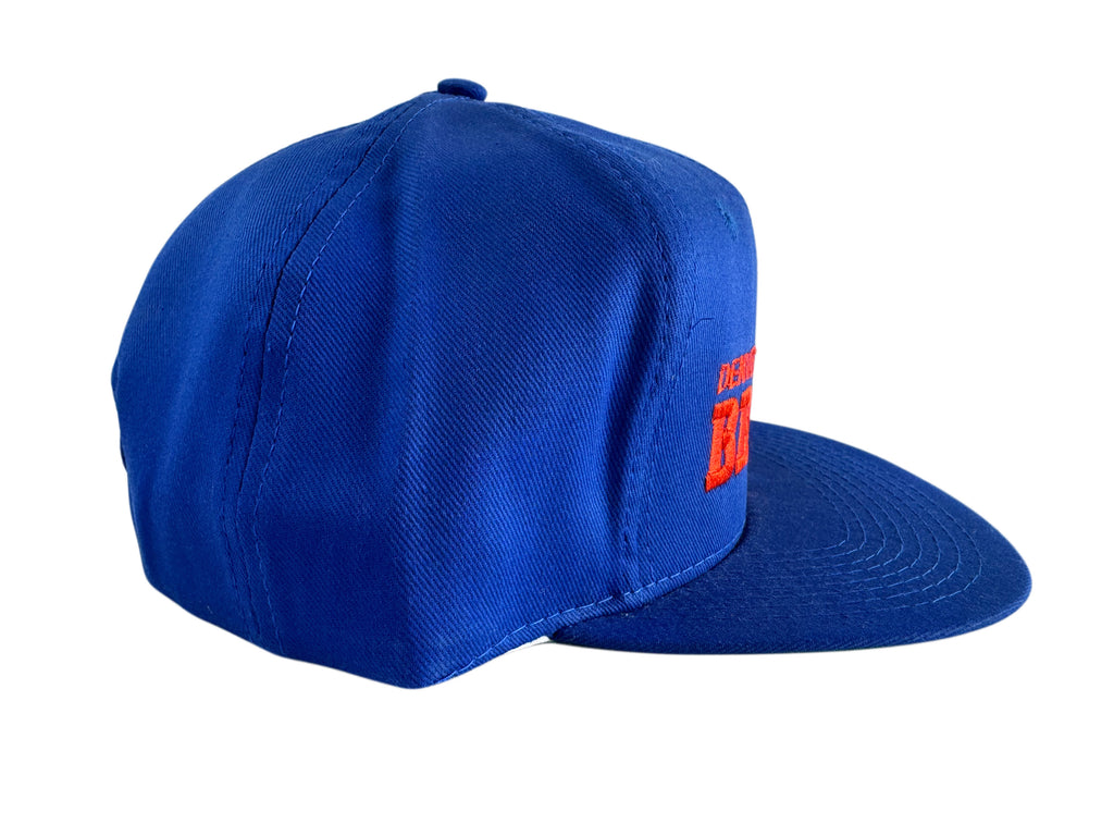 A royal blue flat-brim baseball cap with a small red embroidered logo on the side, shown against a plain white background.