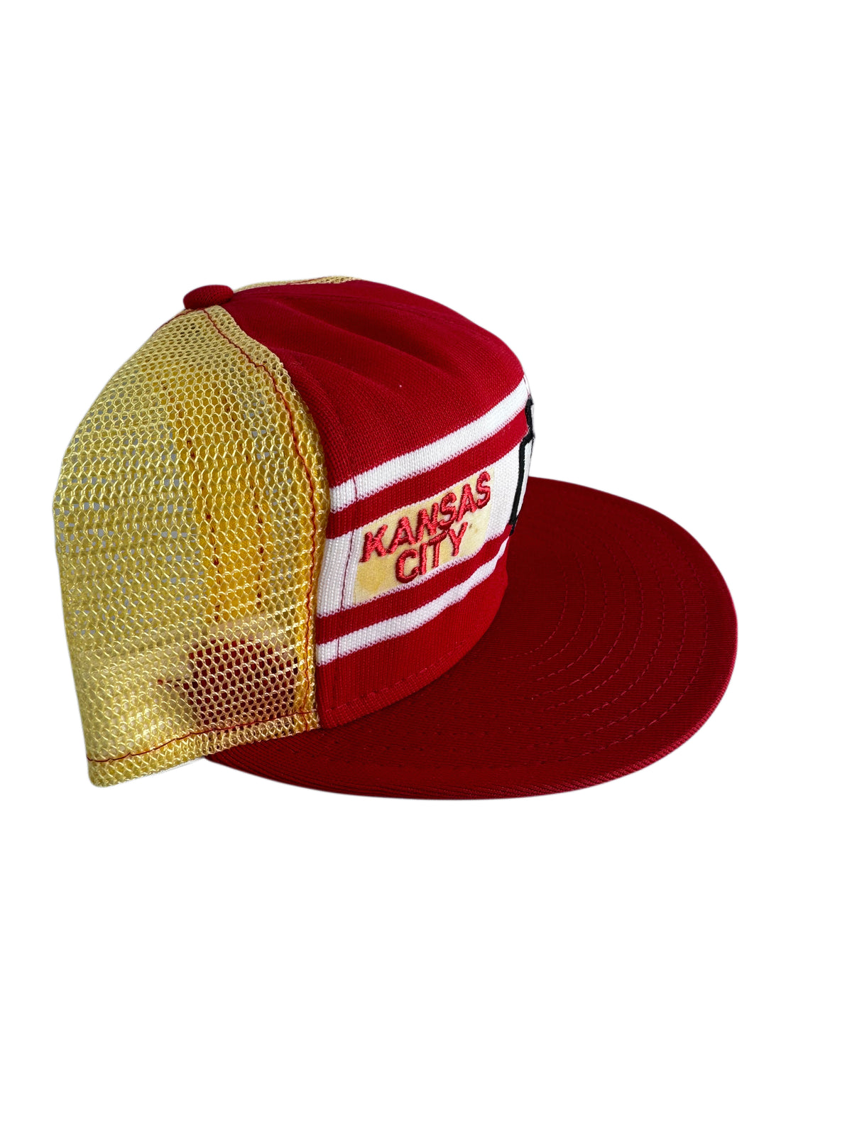A red and gold mesh trucker hat with a white stripe and 'KANSAS CITY' embroidered on the side, shown against a plain white background.