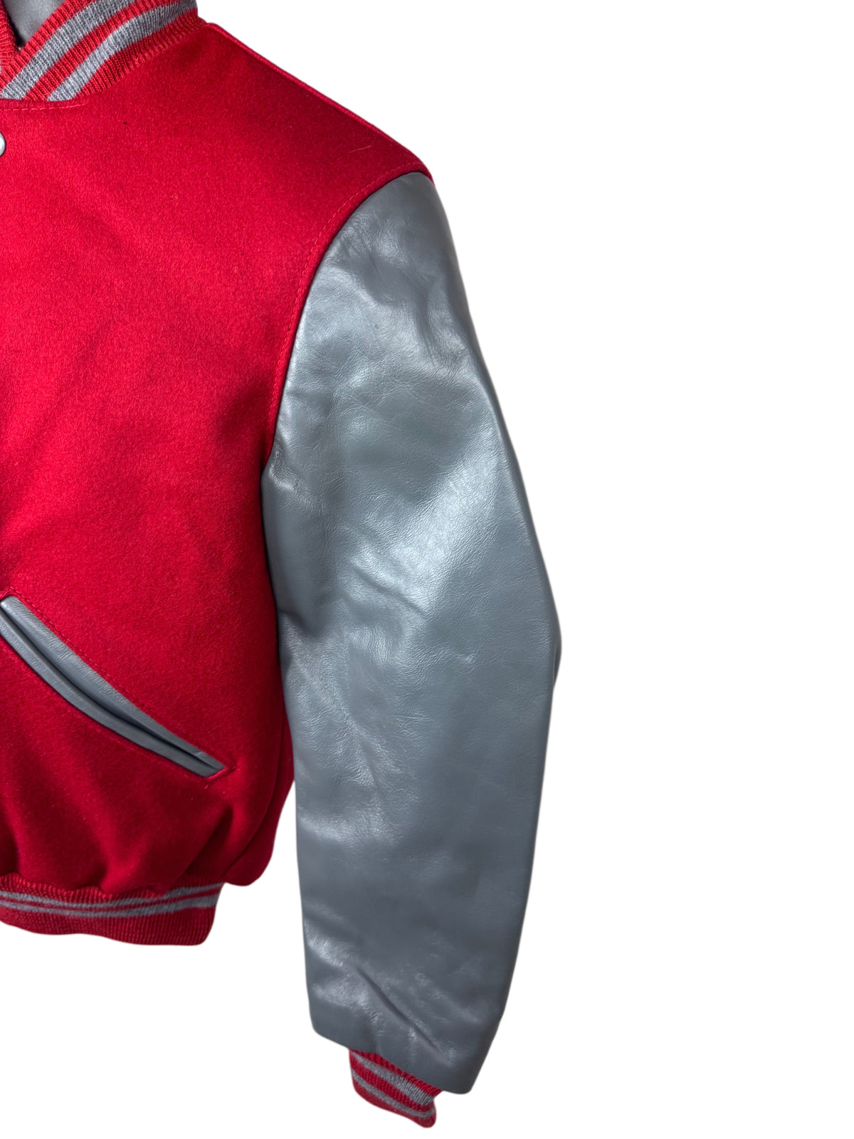 Close-up of a varsity-style jacket showing a red wool body and a shiny silver leather sleeve, with striped ribbed trim on a white background.