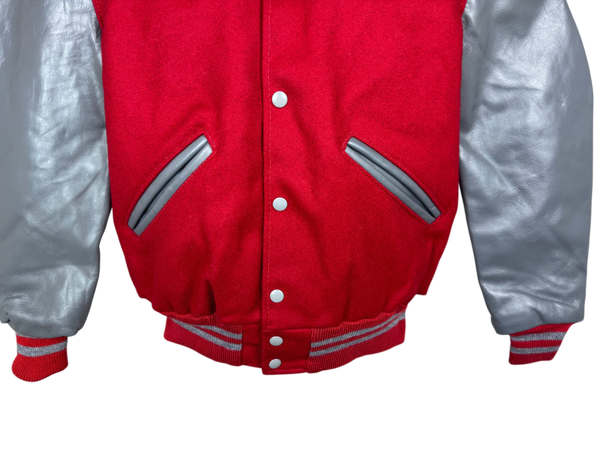 A close-up of a red and silver varsity jacket, showing the red wool body, silver sleeves, and silver details on the pockets.