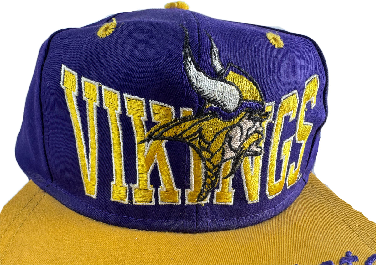 A purple Minnesota Vikings baseball cap with yellow embroidered lettering and a large embroidered team logo on the front, shown against a white background.