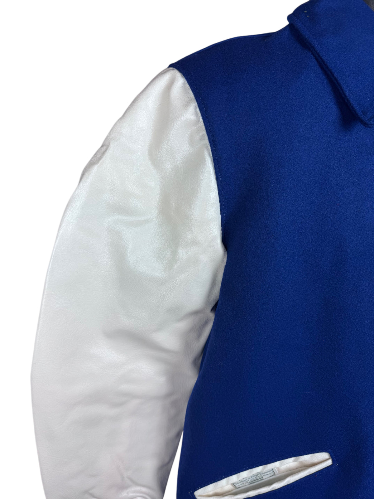 Close-up of a varsity-style jacket sleeve and torso showing a royal blue body with a white naugalite sleeve.