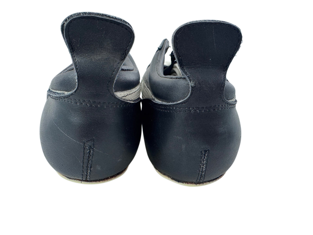 A pair of black leather martial arts kickskis shown from the back, featuring a high heel and a low sole, on a white background.