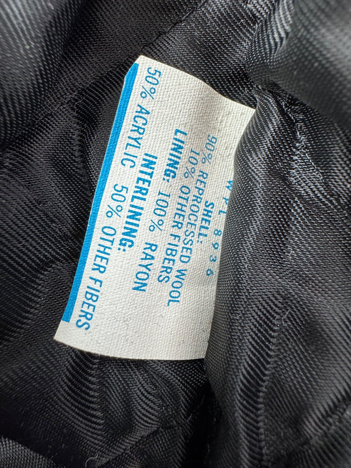 Close-up of a sewn-in fabric inside label Blue DeLong jacket fabric label: 90% reprocessed wool, 10% other fibers; rayon lining; acrylic-blend interlining.