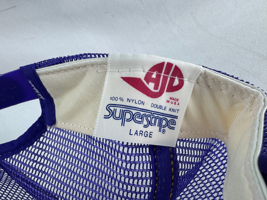 Close-up of the interior label of a vintage blue and white mesh baseball cap, showing the AJP Superstripe brand and size Large.