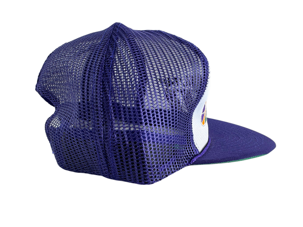 A purple trucker-style cap with a mesh back and a flat visor, shown from a three-quarters angle on a white background.