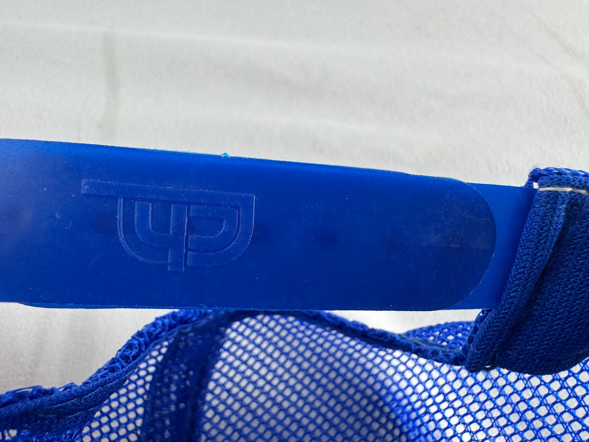 Close-up of a blue mesh strap with a molded embossed logo on a solid blue plastic bar, set against a white fabric background.