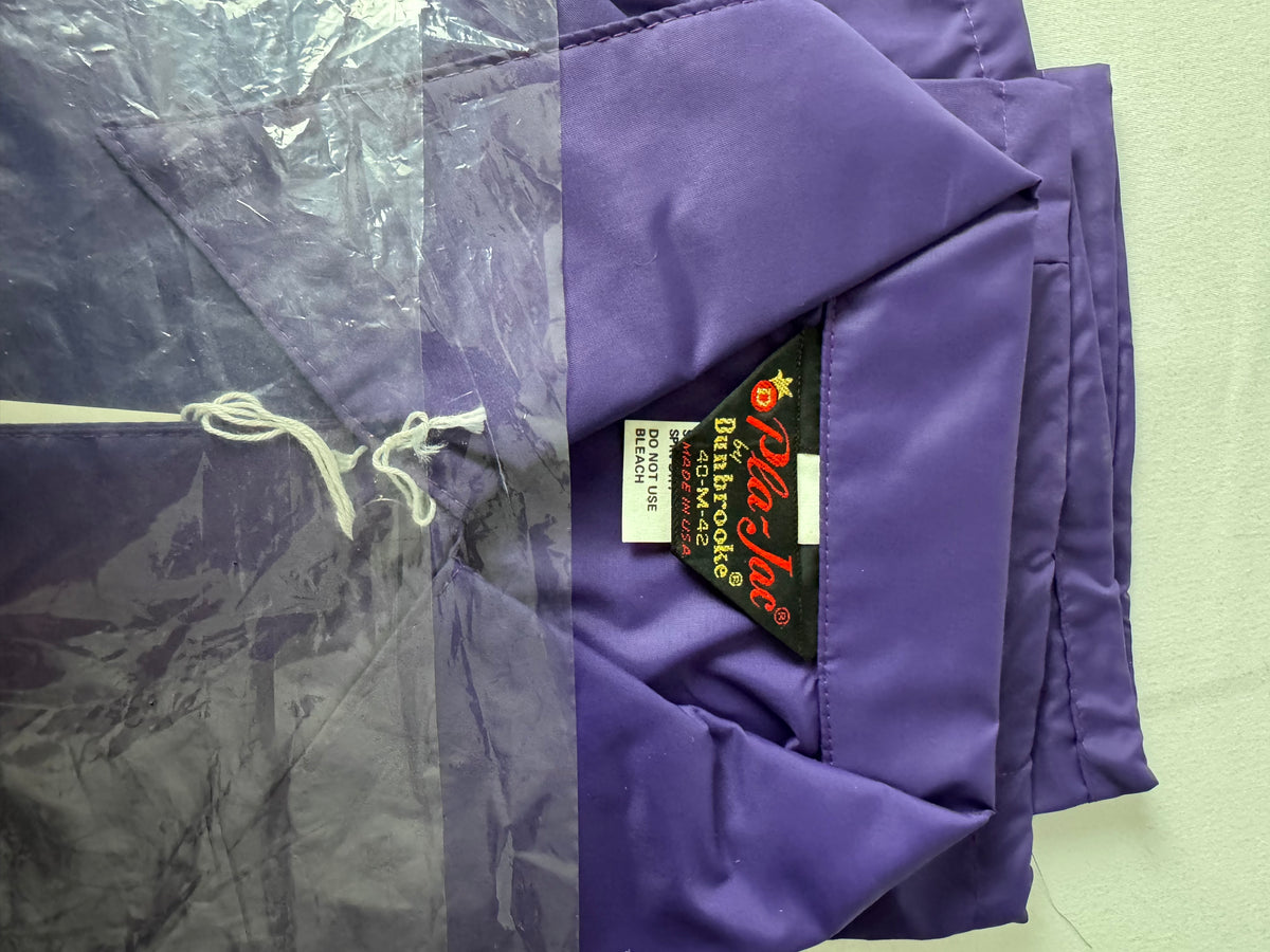 A folded purple nylon jacket shown with its clear plastic garment bag on the left and a black interior label reading 'Pla-Jac by Dunbrooke'  on the right.