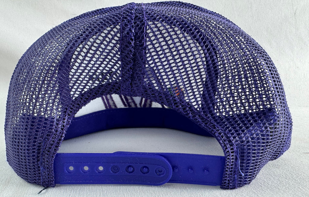 A purple mesh-back trucker cap shown from the back, featuring a solid purple adjustable strap and padded back panel, photographed against a light textured background.