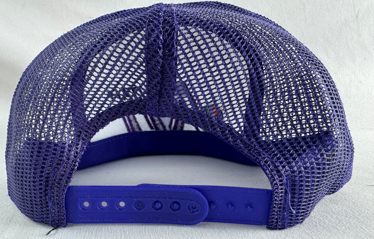 A purple mesh-back trucker cap shown from the back, featuring a solid purple adjustable strap and padded back panel, photographed against a light textured background.