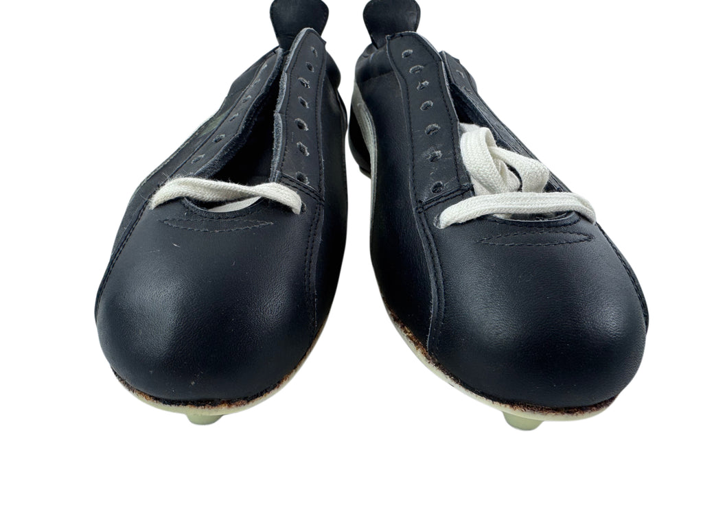 A pair of vintage black leather soccer/football shoes with white laces and white rubber tips, shown against a plain white background.